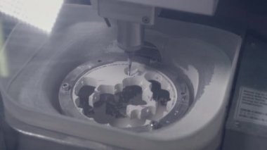 Profesyonel bir CNC makinesi otomatik olarak bir diş protezi yaratır. Matkap seramik çene taklidi yapıyor. Dişçilikte gelişmiş teknoloji. Diş implantı üretimi