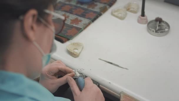 Eine erwachsene Medizinerin stellt im Labor unsichtbare Zahnspangen her. Der Chirurg hält das herausnehmbare Invisalign in seinen Händen. Fortschrittliche Technologie in der Zahnmedizin. Herstellung künstlicher Zähne. — Stockvideo