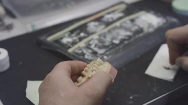 Een tandarts maakt een model van een kaakprothese en keramische tanden in het laboratorium. Breng verf aan op tandheelkundige implantaten met een borstel. Kunstgebit. Toepassing van nieuwe technologieën in de tandheelkunde — Stockvideo