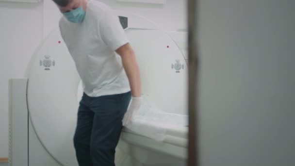 Un pacient cu o mască medicală de protecție se află într-un aparat modern de tomografie computerizată. Medicul analizează plămânii pe un scaner CT. Pericolul de coronavirus sau covid. Scanări pulmonare umane . — Videoclip de stoc