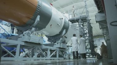 İki mühendis uzay gemisini inceliyor, tablete yazıyor. Askeri bir hangarda fırlatılmaya hazır bir uzay roketi. Uzay teknolojileri. Big Rocket 'in inşaatı. Uzayda İnsanlık.