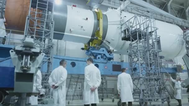 Two scientist engineers inspect the spacecraft, write on the tablet. A space rocket in a military hangar being prepared for launch. Space technologies. Construction of Big Rocket. Humanity in Space. — Stock Video