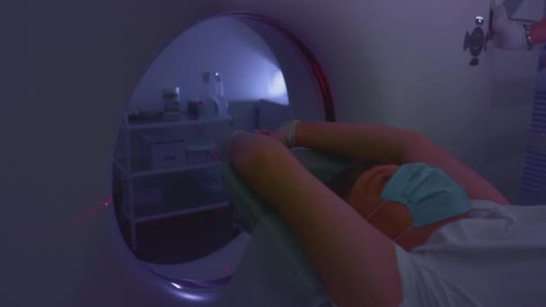 Un paciente con una máscara médica protectora se encuentra en un moderno aparato de tomografía computarizada. El médico analiza los pulmones con una tomografía computarizada. El peligro de covidio o coronavirus. Exploración pulmonar humana. — Vídeos de Stock