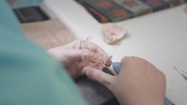 Yetişkin kadın doktor laboratuvarda görünmez diş telleri yaratıyor. Cerrah, Invisalign 'i çıkarılabilir olarak elinde tutuyor. Dişçilikte gelişmiş teknoloji. Yapay diş üretimi.