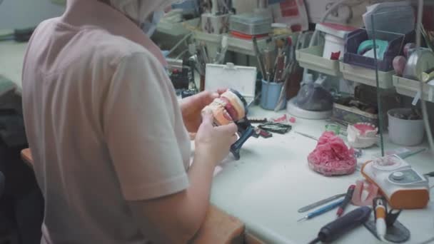 Médico femenino adulto crea una mandíbula dentaria en el laboratorio. Cirujano sosteniendo una prótesis dental. Tecnología avanzada en odontología. Producción de implantes dentales y dientes artificiales. EPIC ROJO. — Vídeos de Stock