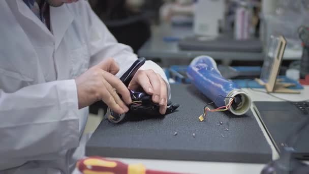 Инженер-учёный создает или диагностирует роботизированный протез руки. Протезная лаборатория, промышленное производство. Механическая рука для полноценной жизни. Создание кибернетических конечностей. Помощь ампутантам — стоковое видео