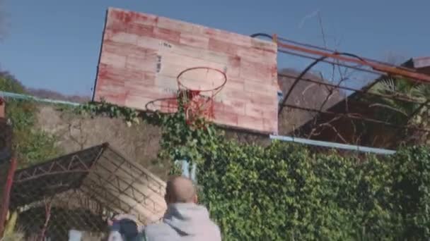 Der Spieler wirft den Ball erfolgreich in den Reifen, erzielt einen Punkt, ein Drei-Punkte-Tor. Ein Mann dribbelt auf einem Straßenhof, wirft einen Ball in einen Basketballkorb. Sportliche Motivation — Stockvideo