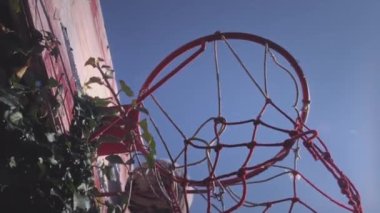 Yukarıya doğru, bir basketbol topu spor sahasında sepete çarpıyor. Oyuncu topu başarılı bir şekilde potaya fırlatıyor, bir sayı, üç sayı. Sokak ve spor motivasyonu. Yavaş çekim.