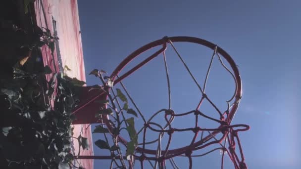 Vista hacia arriba, una pelota de baloncesto golpea la canasta en el patio de deportes. El jugador lanza con éxito la pelota en el aro, marca un punto, un gol de tres puntos. Motivación callejera y deportiva. Movimiento lento. — Vídeos de Stock