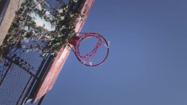 Yukarıya doğru, bir basketbol topu spor sahasında sepete çarpıyor. Oyuncu topu başarılı bir şekilde potaya fırlatıyor, bir sayı, üç sayı. Sokak ve spor motivasyonu. Yavaş çekim.