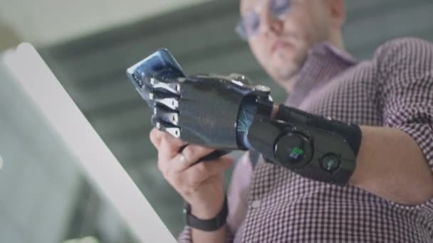 Człowiek z bioniczną futurystyczną ręką używa smartfona. Mężczyzna z protezą ręki używa smartfona. Pisze wiadomość lub przewija portale społecznościowe. Nowoczesne technologie dla osób niepełnosprawnych. Człowiek cyborg. — Wideo stockowe