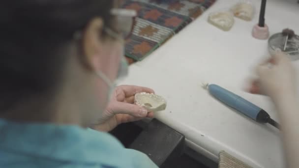 Volwassen vrouwelijke arts creëert onzichtbare beugels in het laboratorium. De chirurg houdt de Invisalign verwijderbaar in zijn handen. Geavanceerde tandheelkundige technologie. Productie van kunsttanden. — Stockvideo