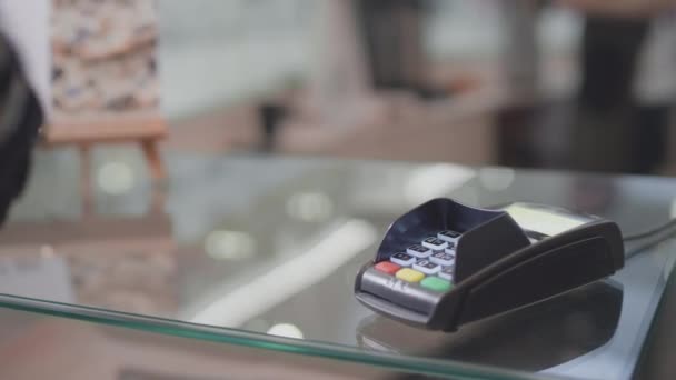 Um homem com um braço protético usa um smartwatch. Paga pela compra através do terminal pos no café. chip NFC em um braço robótico. Tecnologias modernas para pessoas com deficiência — Vídeo de Stock