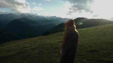 Günbatımında dağın zirvesine doğru esen rüzgârda gelişen uzun elbiseli hippi genç bir bayanı izleyen kamera kollarını havaya kaldırıyor, hayattan, gençlikten ve mutluluktan sarhoş olarak.