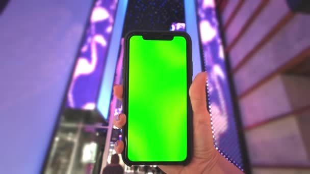 Ruka drží smartphone se zelenou obrazovkou na pozadí neonových světel nákupního centra v Las Vegas. Módní večerní nákupy — Stock video