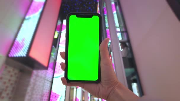 Ręka trzyma smartfona z zielonym ekranem na tle neonów w centrum handlowym w Las Vegas. Modne wieczorne zakupy — Wideo stockowe