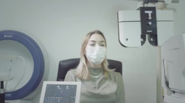 Kız hasta göz doktorunun muayenehanesinde görüşü kontrol ediyor. Gözleri iyileştirir, görüşü düzeltir. Görme yetisini kontrol etmek için tıbbi bir cihaz. Doktor hasta göz testi yapıyor..