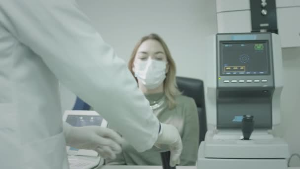 Una paciente chequea la vista en el consultorio de oftalmólogos. Cura los ojos, restaura la visión. Un dispositivo médico para comprobar la vista. Médico que trabaja con pruebas oculares para pacientes. — Vídeo de stock