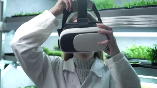 Una chica científica o un médico en el laboratorio se pone gafas de realidad virtual. Nuevas tecnologías en ciencia y medicina. Estanterías de microecologización genéticamente modificada. Utiliza inteligencia artificial. — Vídeos de Stock