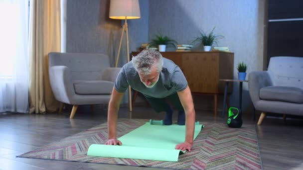 Portrait d'un homme âgé aux cheveux gris, faisant de l'exercice push-up, de l'entraînement. Accueil mouvements sportifs avec les articulations du dos et des bras. Grand-père en excellente forme de corps sportif. Vieil homme en vêtements de sport — Video
