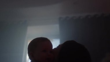 Genç Avrupalı anne ve küçük oğlu yatakta sarılıyorlar. Kız bebeği kustu. Çocuk eğleniyor ve gülüyor. Aile değerleri. Doğum izni, ev konforu