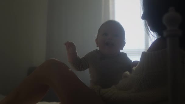 Jonge Millennial moeder en zoontje in bed. De jongen kijkt glimlachend naar de camera. Gezinswaarden. Zwangerschapsverlof, huiselijk comfort — Stockvideo