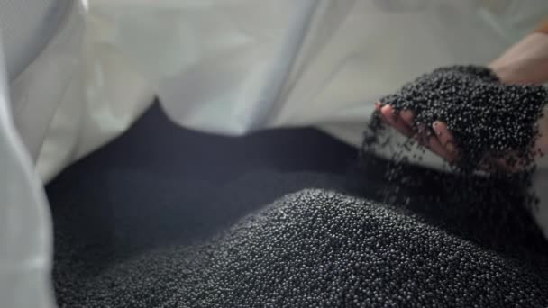 Le mani sollevano granuli polimerici da un sacchetto in un impianto di riciclaggio dei rifiuti. — Video Stock