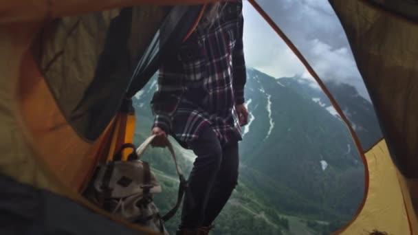 Young girl hiker in a plaid shirt. He takes a backpack from the yellow tent and runs to the peaks, hands up — Stock Video