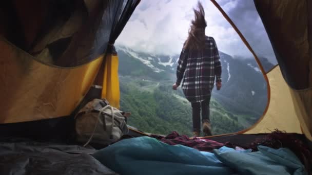Mladá dívka turistka v kostkované košili zvedne ruce na pozadí hor — Stock video