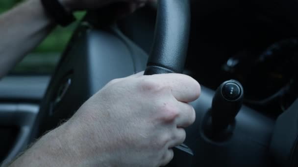 De man bestuurt de auto. Close-up van een zwart leren stuurwiel in zijn handen. Reizen op de snelweg — Stockvideo