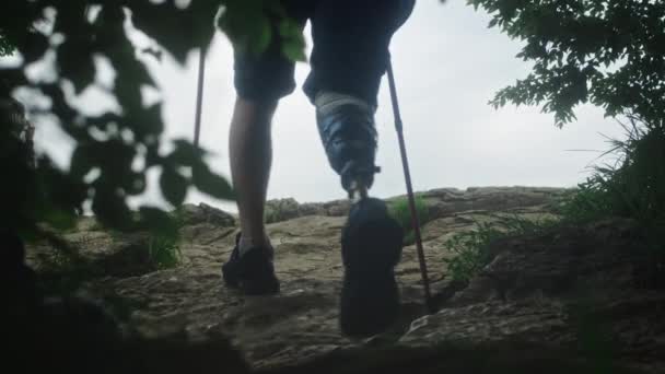 Άνδρας πεζοπόρος με προσθετικό πόδι. Ο ανάπηρος διασχίζει βράχους, απολαμβάνοντας το ταξίδι του στα βουνά. — Αρχείο Βίντεο