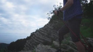 Protez bacaklı bir erkek yürüyüşçü. Engelli adam kayaları kırıp, dağlara seyahatinin tadını çıkarıyor.