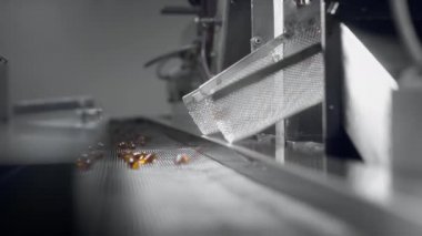 Sarı jel kapsüller tıbbi makinenin taşıyıcı bandında hareket eder.