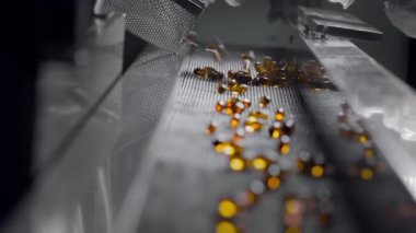 Sarı jel kapsüller tıbbi makinenin taşıyıcı bandında hareket eder.