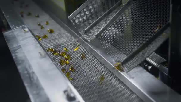 Gele gel capsules bewegen op de transportband van de medische machine — Stockvideo