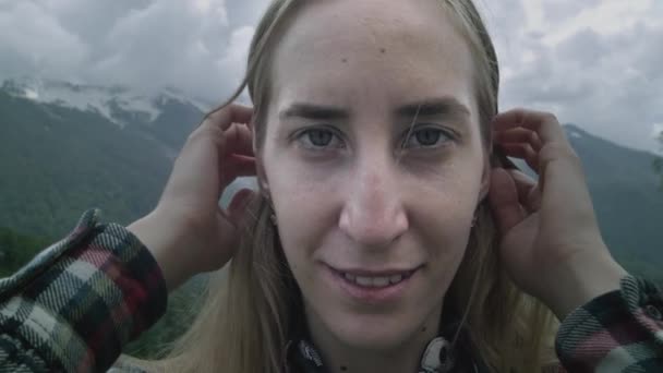 Porträt eines jungen Mädchens vor dem Hintergrund der Berge. Die Frau lächelt und blickt in die Kamera. Reisen in den Bergen — Stockvideo