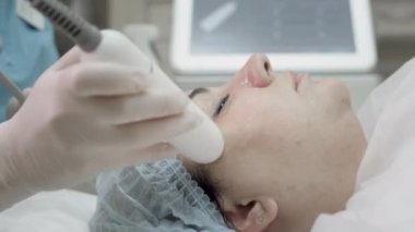 Yüzün kadın derisinde estetik ameliyat. Cerrahi olmayan kırışıklık giderici. Terapist bir kadın müşteriye plazma kaldırma işlemi yapıyor..