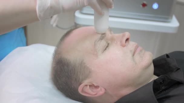Cosmetische ingreep op de mannelijke huid van het gezicht. Niet-chirurgische rimpelopheffing. De therapeut tilt plasma op naar een mannelijke cliënt.. — Stockvideo