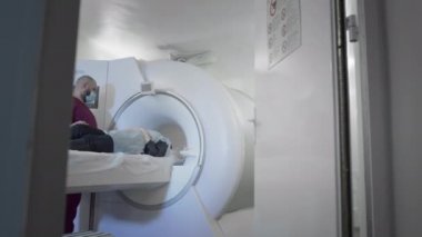 Doktor modern bir klinikte bir hastanın MR veya PET taramasını yapar. Yatakta üç boyutlu tarama makinesinin içindeki kız. Kadın CT taraması yapıyor.