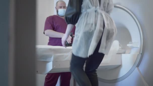Läkaren gör en MRT eller PET-undersökning av en patient på en modern klinik. Flicka på sängen i en 3D-avsökningsmaskin. Kvinnan gör datortomografi — Stockvideo