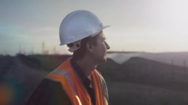 Gün batımında güneş panellerinin yanında genç bir mühendisin portresi. Yenilenebilir enerji kaynakları ve güneş pillerinin sağlığını ve verimliliğini kontrol eder. Güneş paneli plantasyonu. Yeşil enerji kavramı