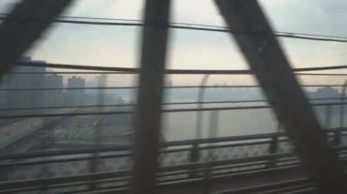 Metro vagonunun penceresinden bak. Elektrikli tren Brooklyn Köprüsü 'nden nehri geçer. Gün doğumunda şehir merkezinin manzarası. New York