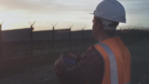 En manlig ingenjör tar ett foto av en plantage eller solpanel anläggning på en smartphone. Inspektioner och kontroller av anläggningens kvalitet — Stockvideo