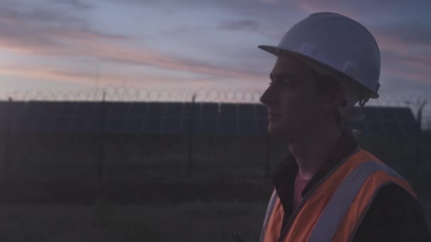 Retrato de um engenheiro trabalhador profissional do sexo masculino perto com painéis solares fazenda. Instalações fotovoltaicas. Tecnologias de energias renováveis — Vídeo de Stock