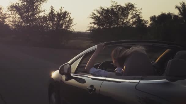 Una joven conduciendo un descapotable comienza a moverse. El comienzo del viaje. Una mujer conduciendo un coche. Sostiene el volante con las manos — Vídeo de stock