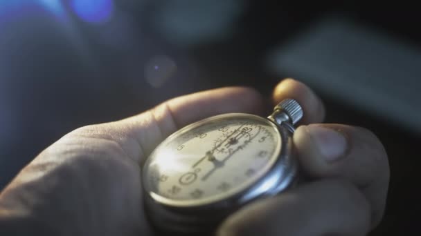 Un cronómetro en la mano de un hombre. Un hombre presiona el botón de un segundo reloj de metal deportivo vintage. Cuenta atrás, temporizador antes del evento. — Vídeos de Stock
