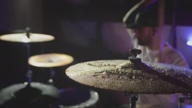 Davulcu davul tokmağı ile ıslak davul ziline vurur ve su yavaş çekimde sıçrar. Müzik aletlerinin kayıt stüdyosunda