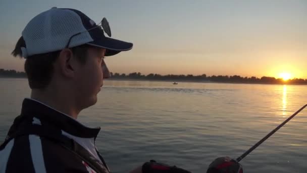 Pescador macho pesca en un barco al atardecer . — Vídeos de Stock