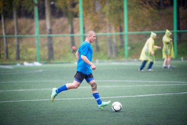 Yağmur sokakta futbol oynayan adam.