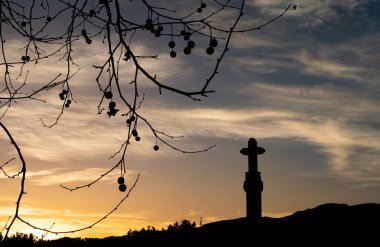 Taştan haç silueti günbatımında arka planda.